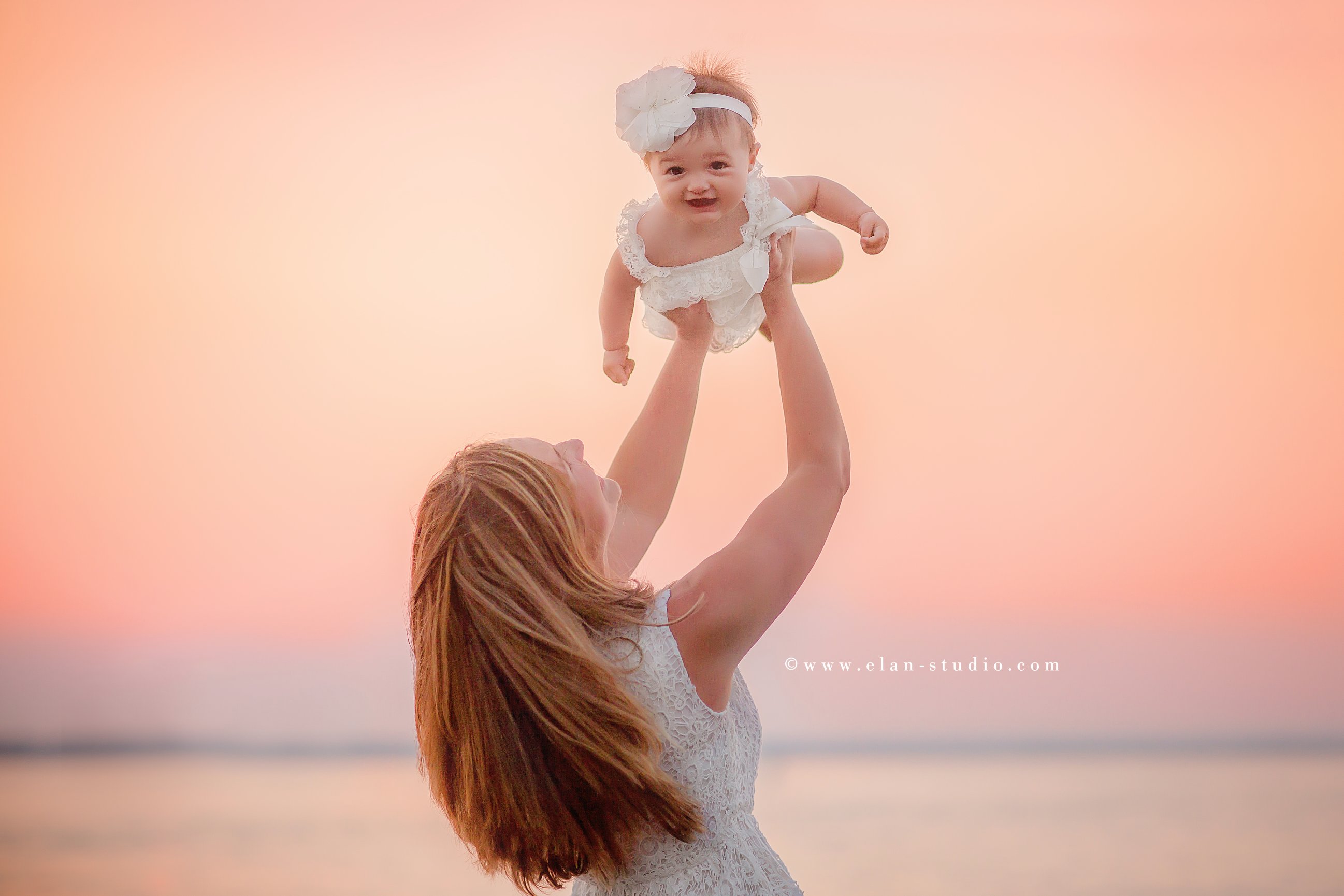 mother twirling with baby daughter smiling at camera