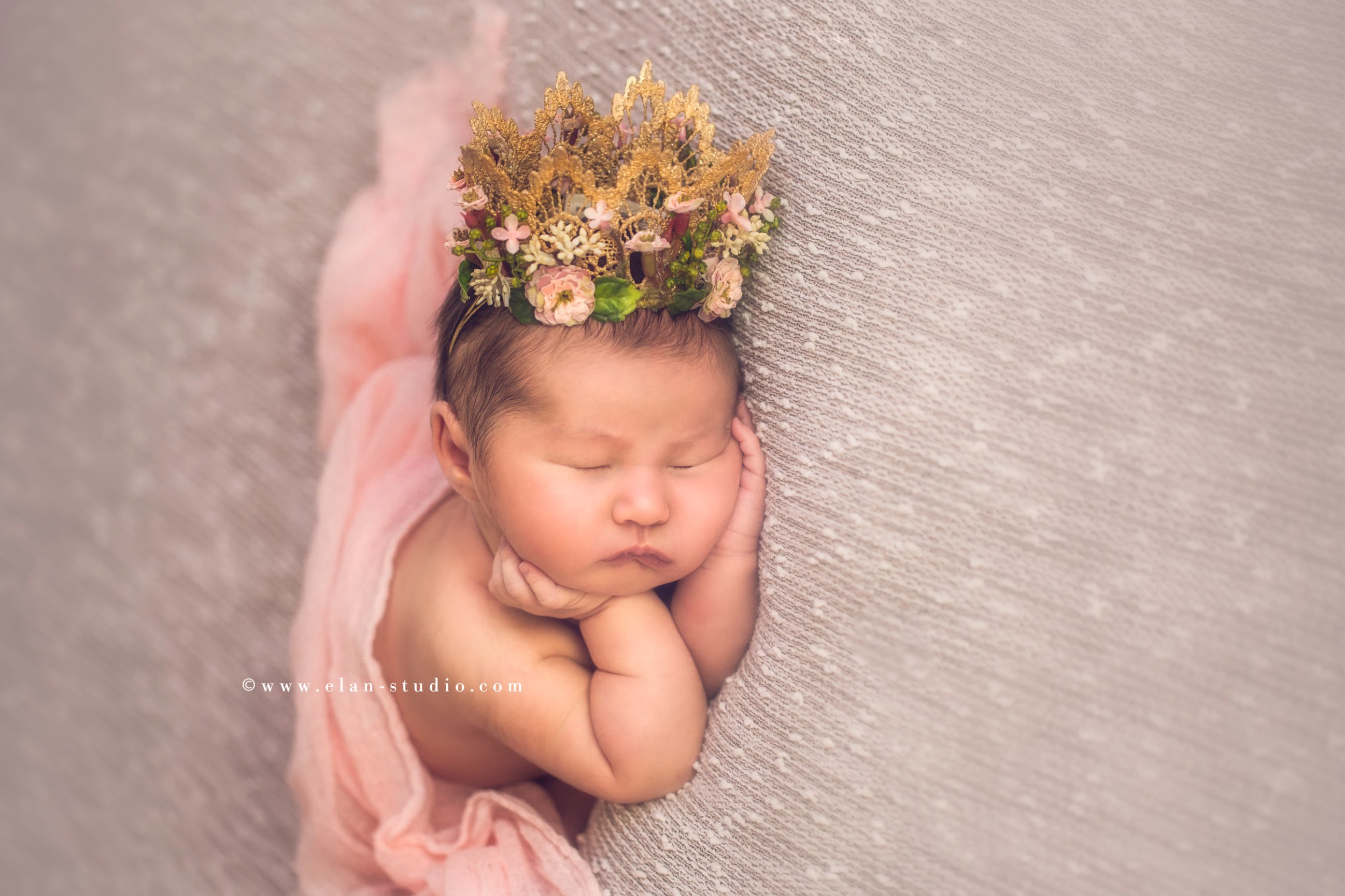 newborn wearing flower crown, on light gray blanket