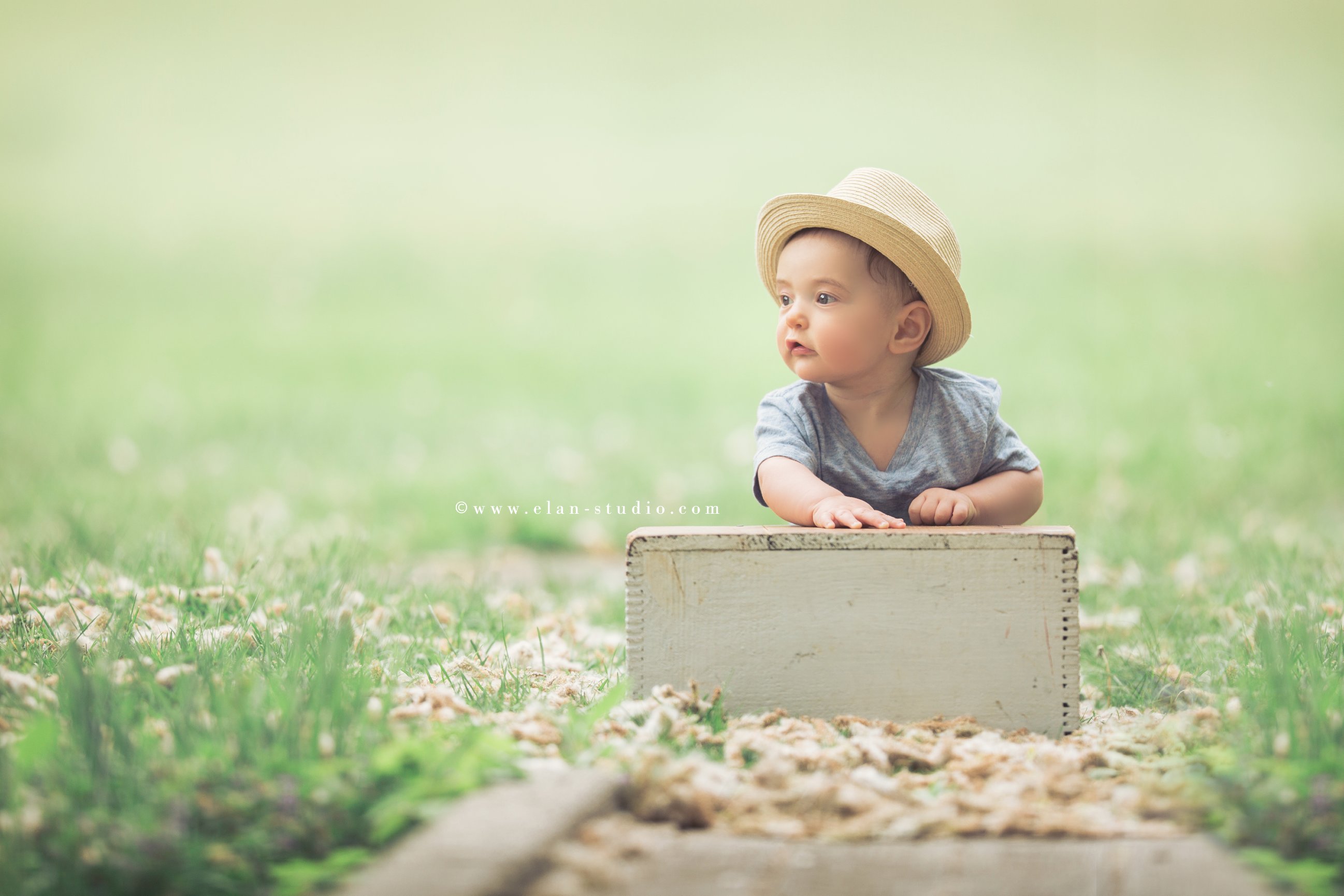 sitting baby boy wearing straw hat and blue chambray shirt