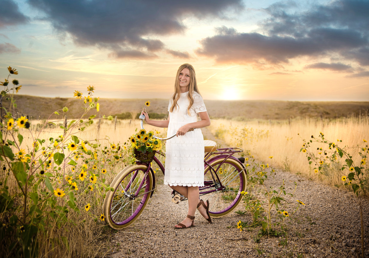 A teen girl with a bike in a sunflower field.