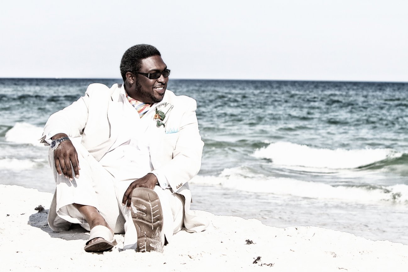 Groom sitting alone on the beach in thoughtful pose