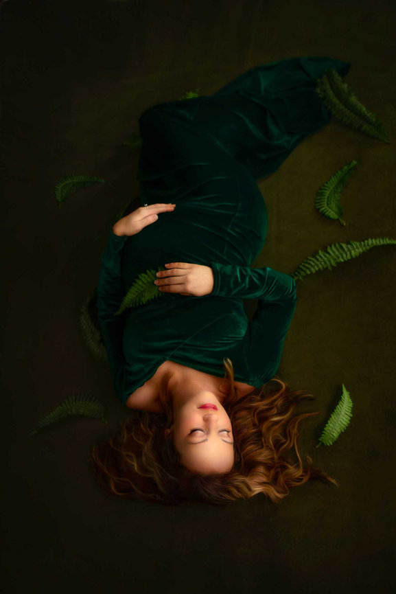 Keller fine art child portrait with girl in green dress lying down surrounded by leaves.