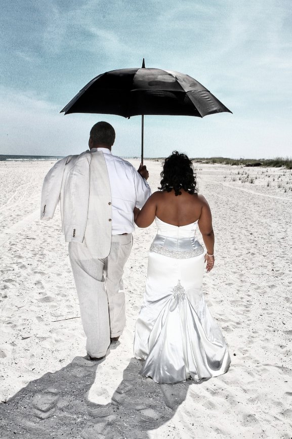 Couple walking on a beach under an umbrella