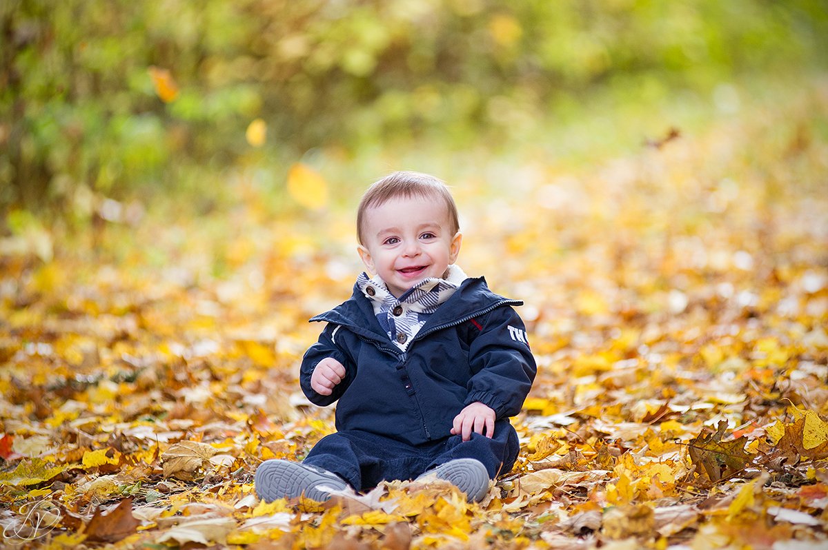 adorable one year old playing in leaves