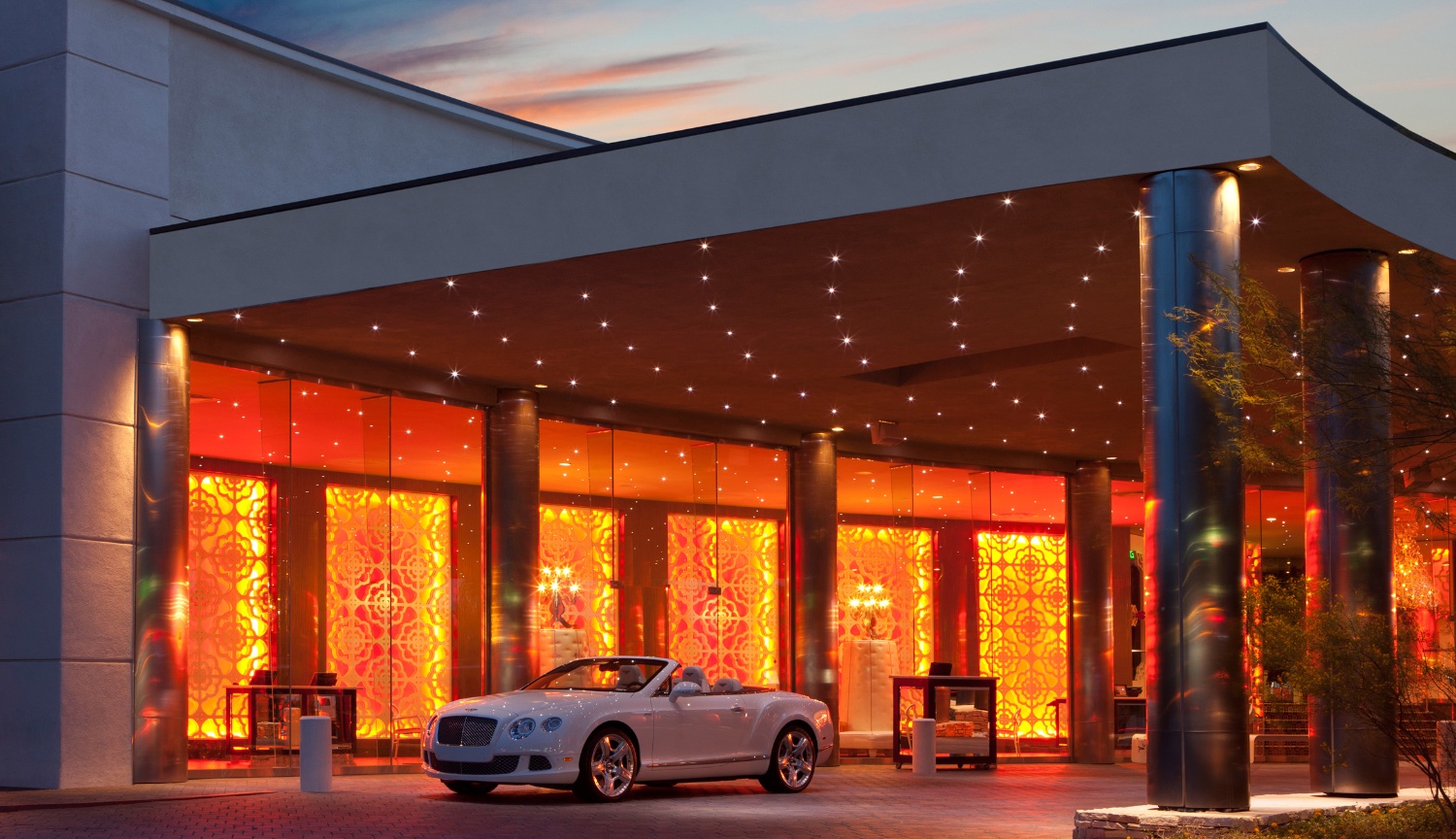 Orange lit Exterior Porte Cache at the Riviera Hotel with convertible Bentley in Driveway in the heart of Palm Springs California.