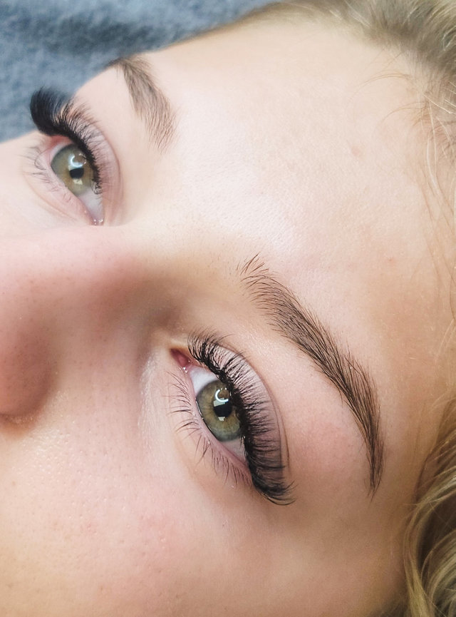 Close-up of a person's eyes with long eyelashes and well-defined eyebrows, focusing on eye and makeup details.