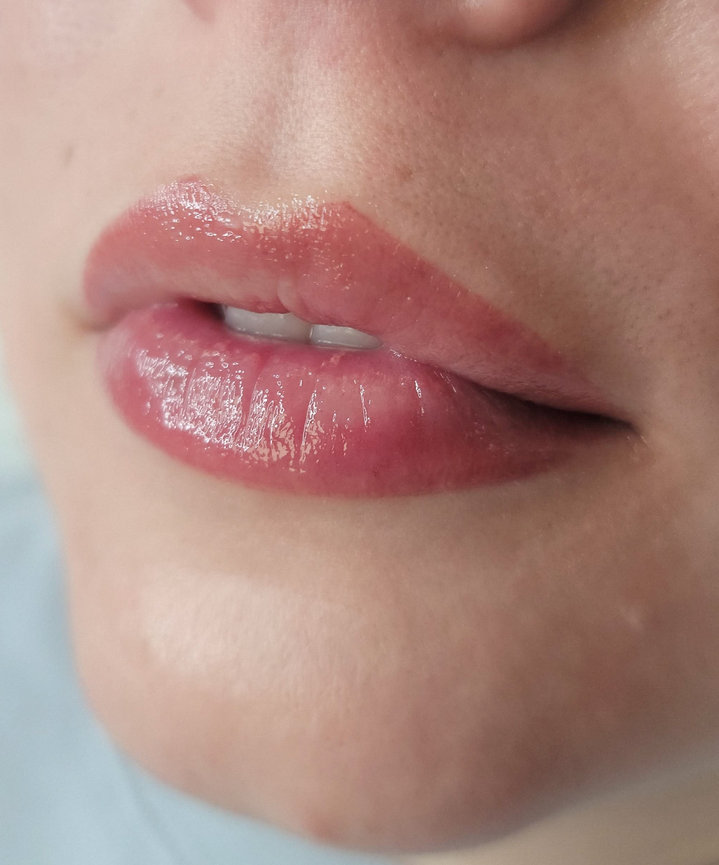 Close-up of a person's lips with glossy pink lip balm applied.