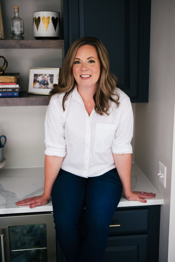 entrepreneur dietitian sits on kitchen bar counter smiling