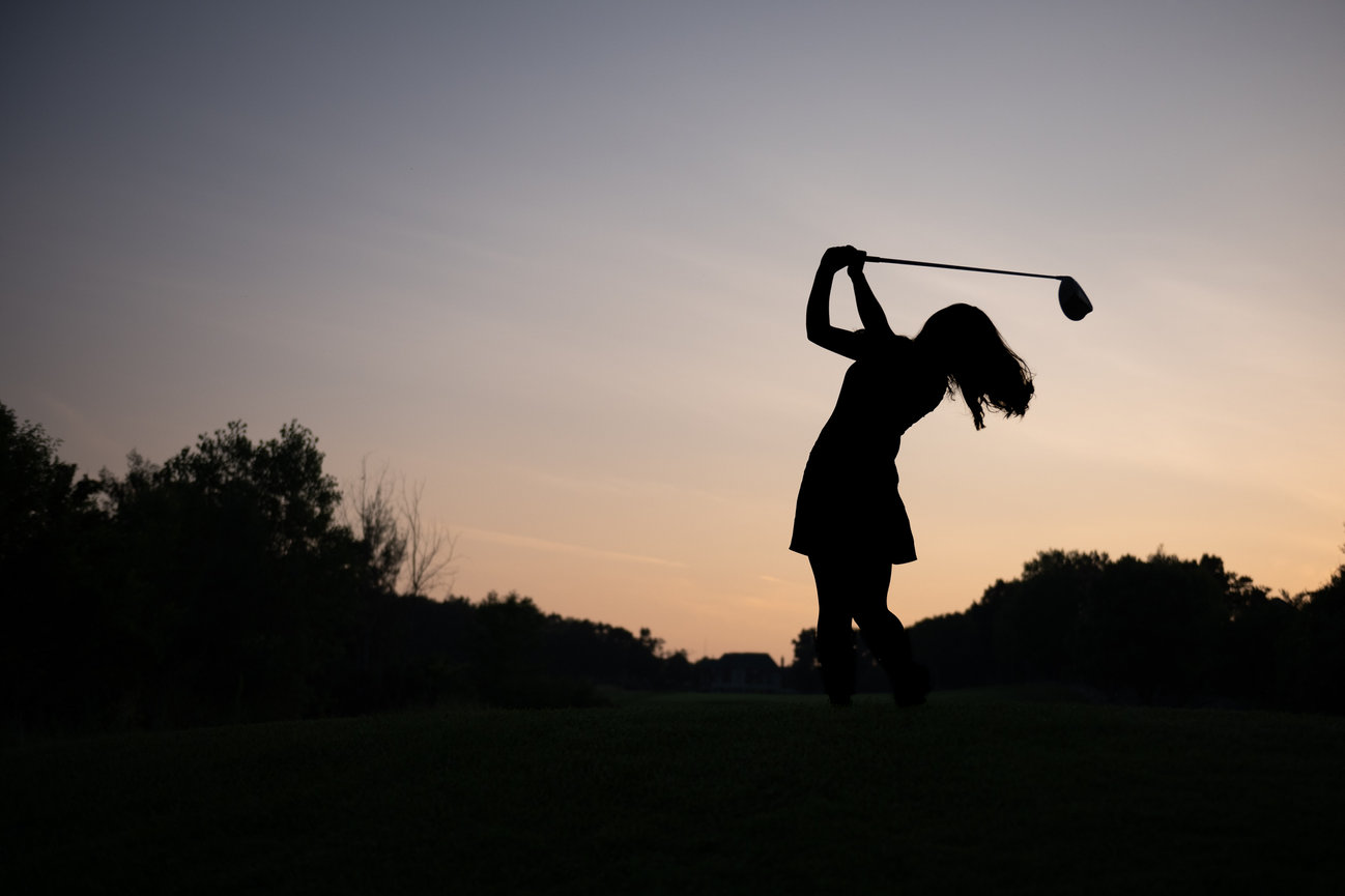 silhouette of female high school golfer against sunset graduation senior picture