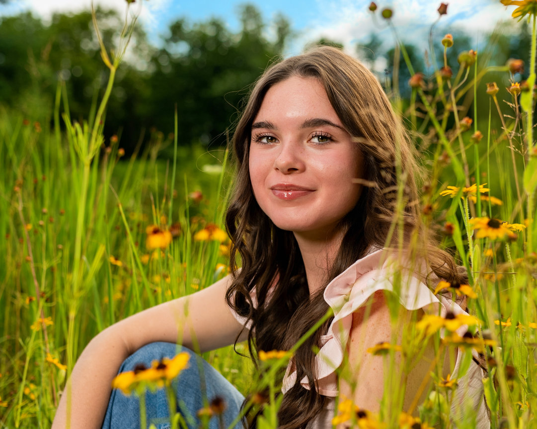west middlesex senior girl sitting in a flower field smiling