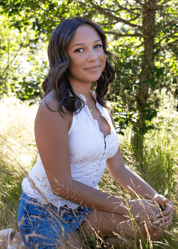 Woman sitting in tall grass during an outdoor portrait session.