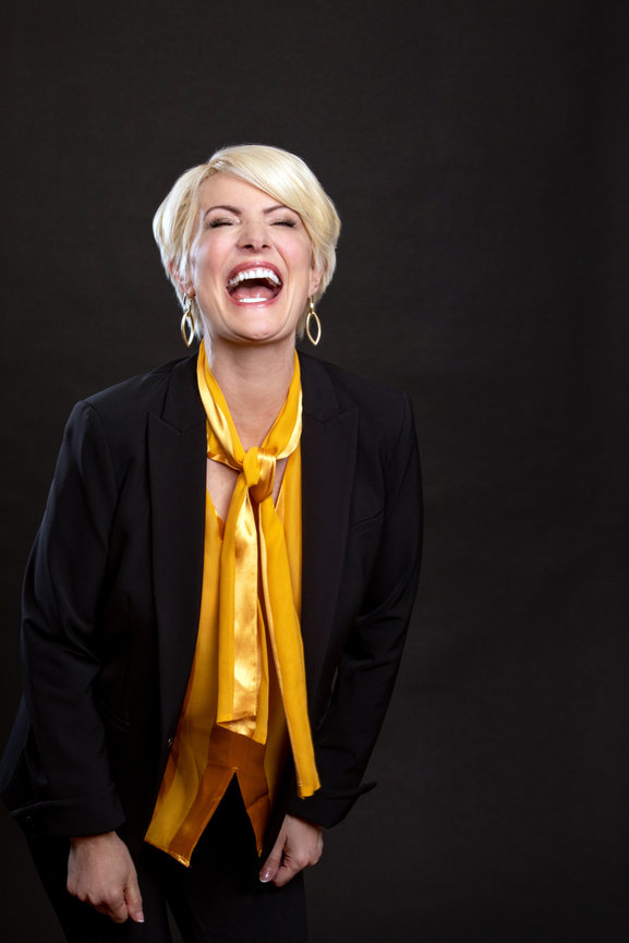 Laughing blonde haired executive woman in gold top with black jacket