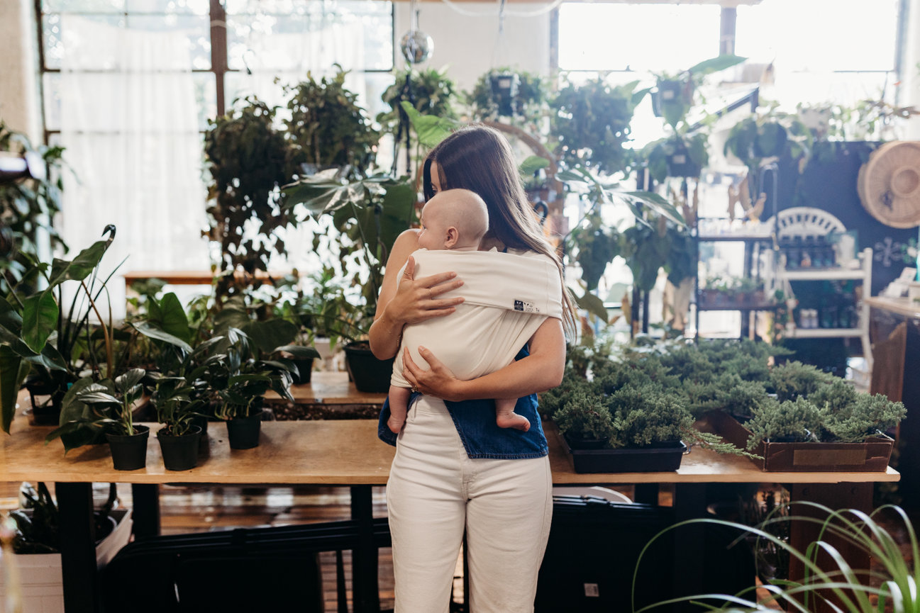 Woman holding baby in baby carrier in Huntsville Alabama greenhouse