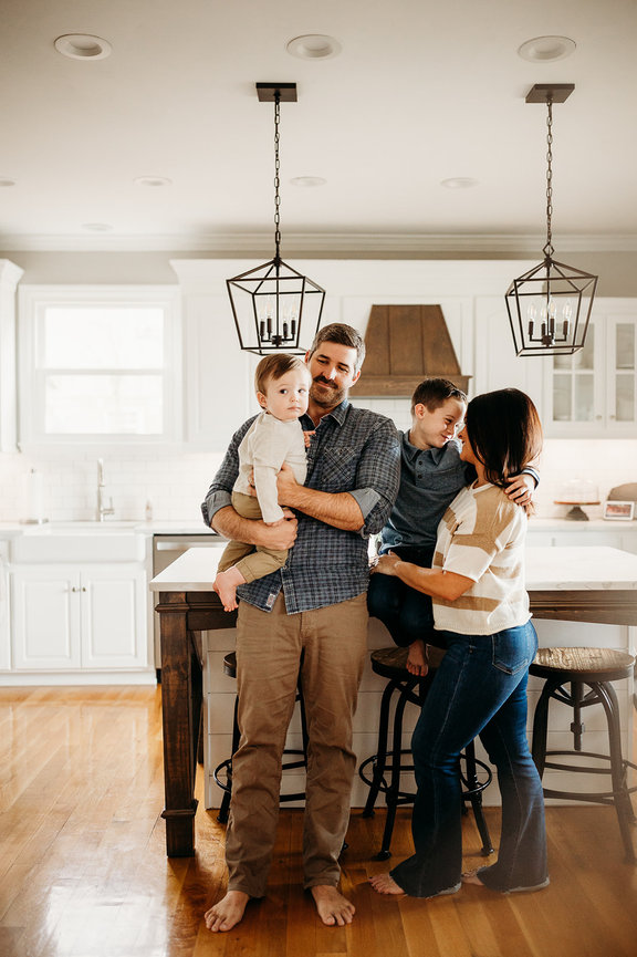 A family of four laugh and stand together in a kitchen in a Huntsville Alabama family photoshoot
