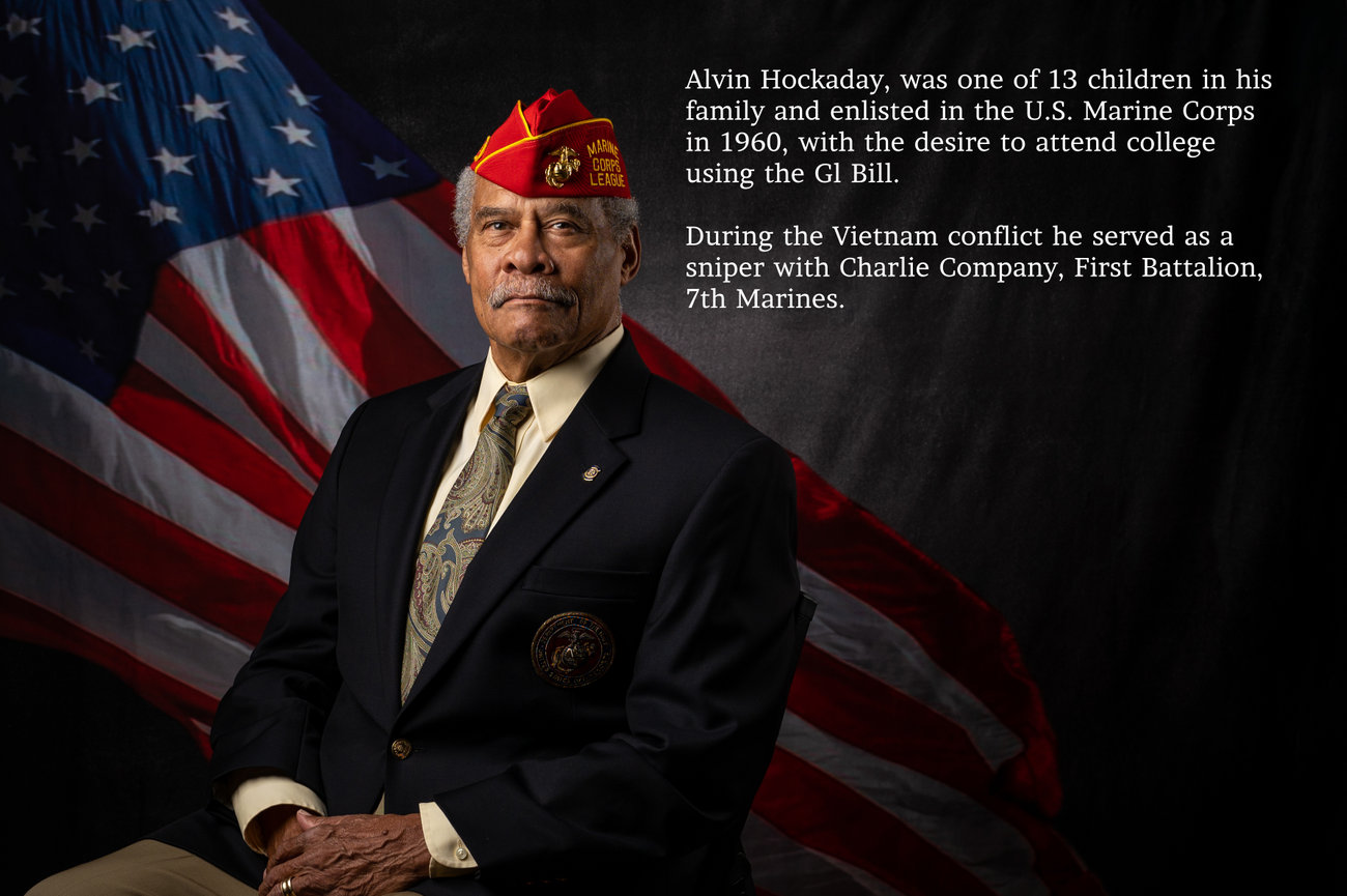 Portrait of a Marine Corps veteran in a red cap with an American flag background and biographical text