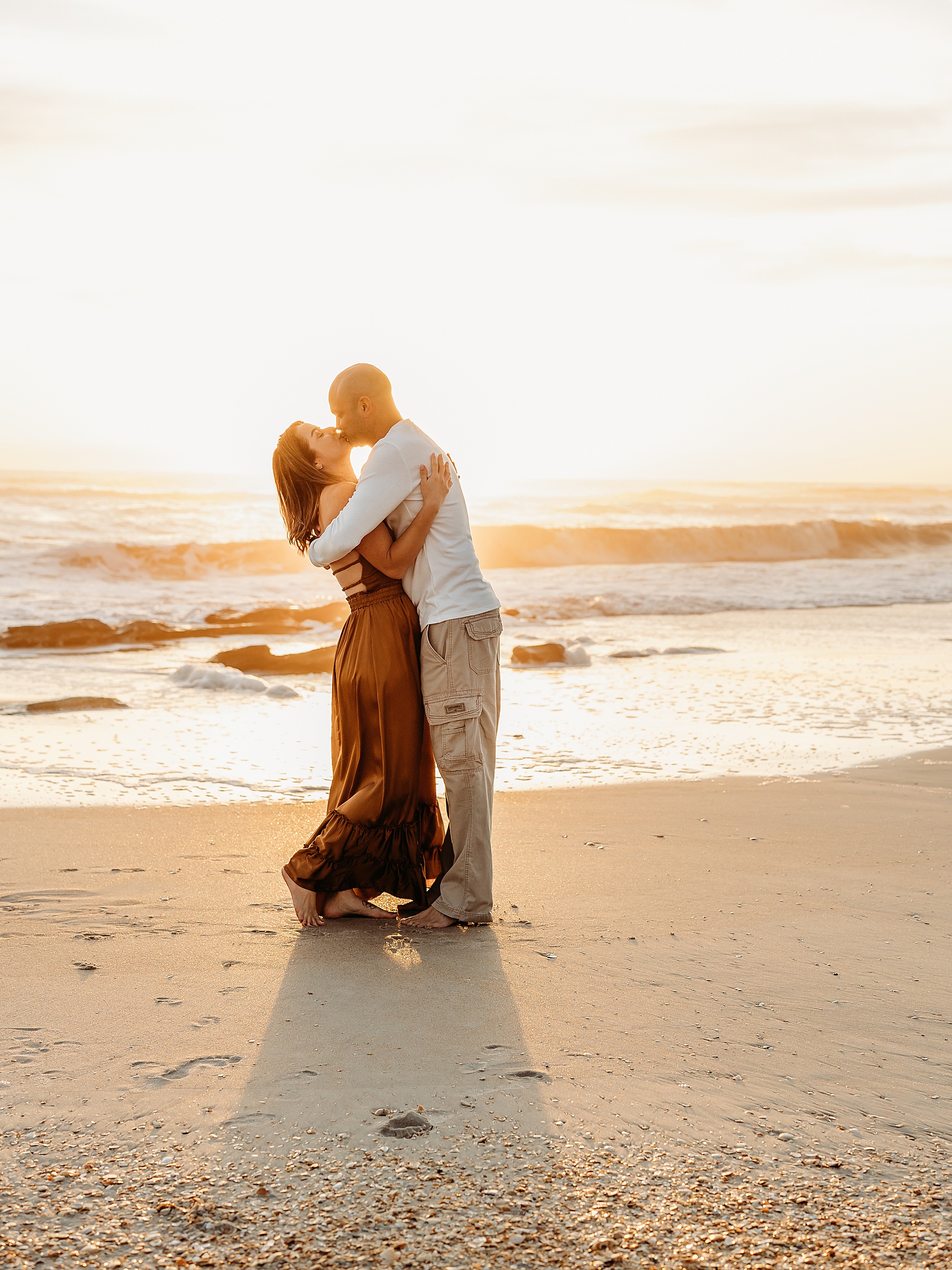 man and woman holding each other at sunrise on the beach