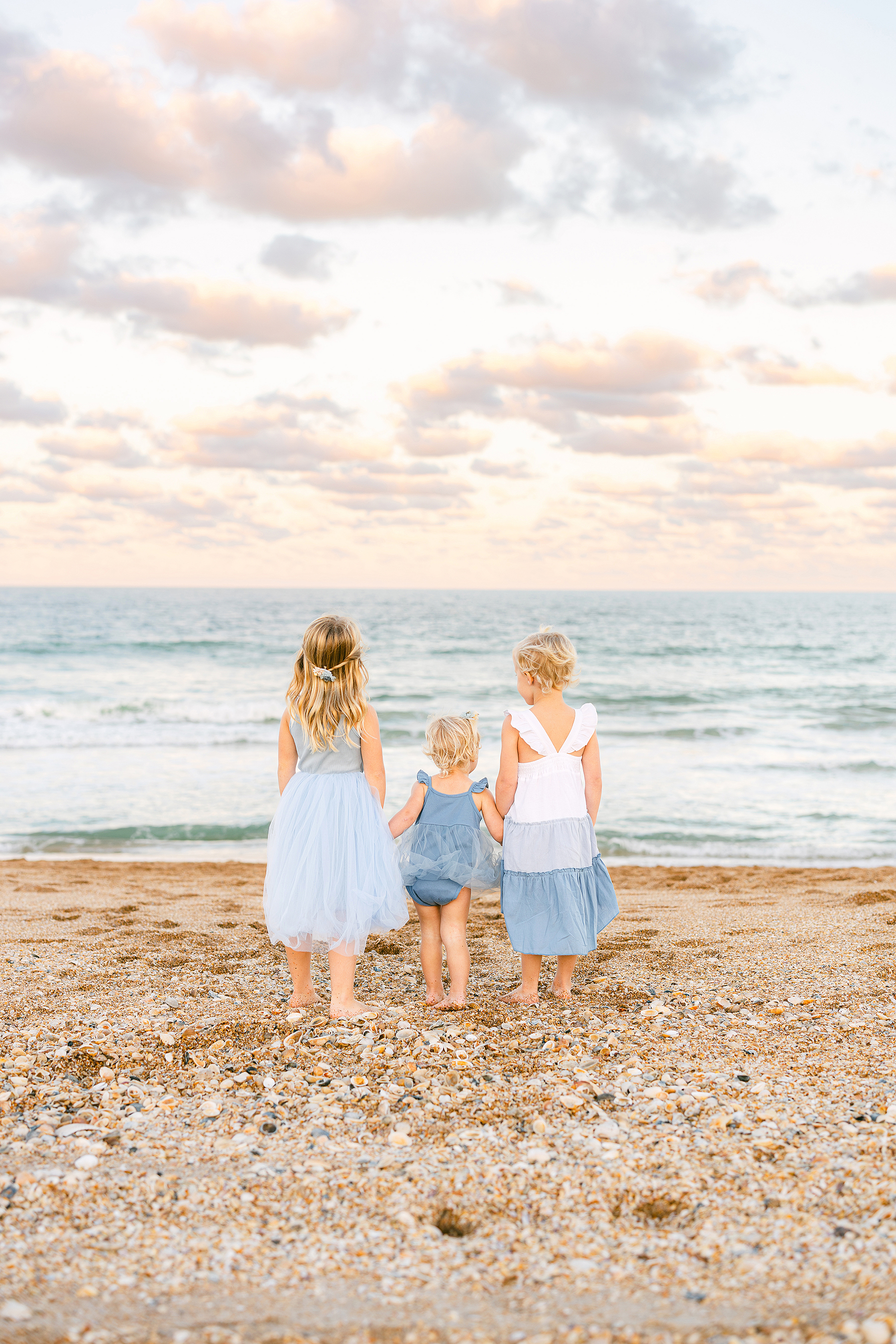 Three little girls standing by the shoreline holding hands on the beach at sunset in Guana State Park at Ponte Vedra Beach.