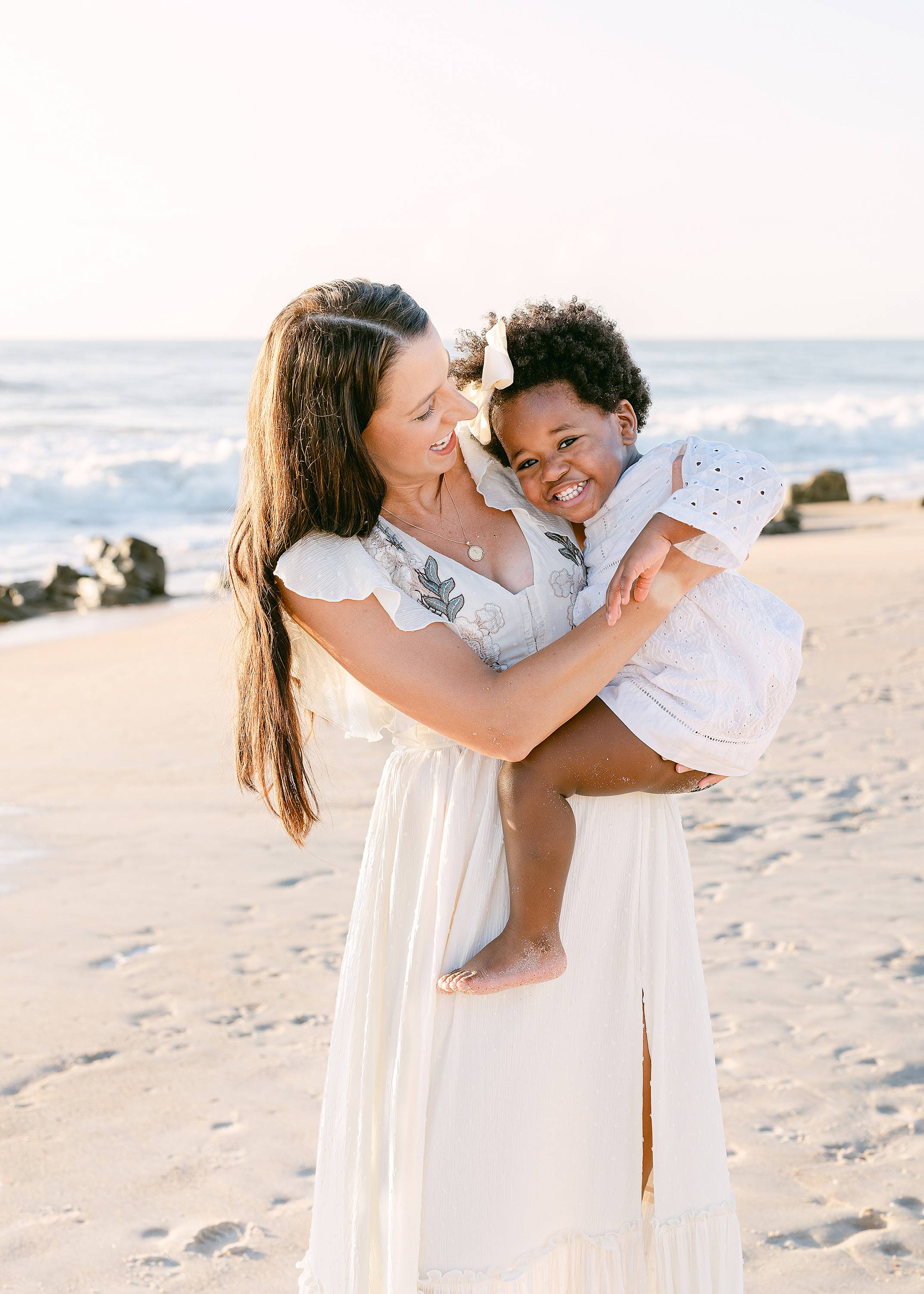 A sunrise motherhood portrait of a woman and her adopted little girl on Saint Augustine Beach.