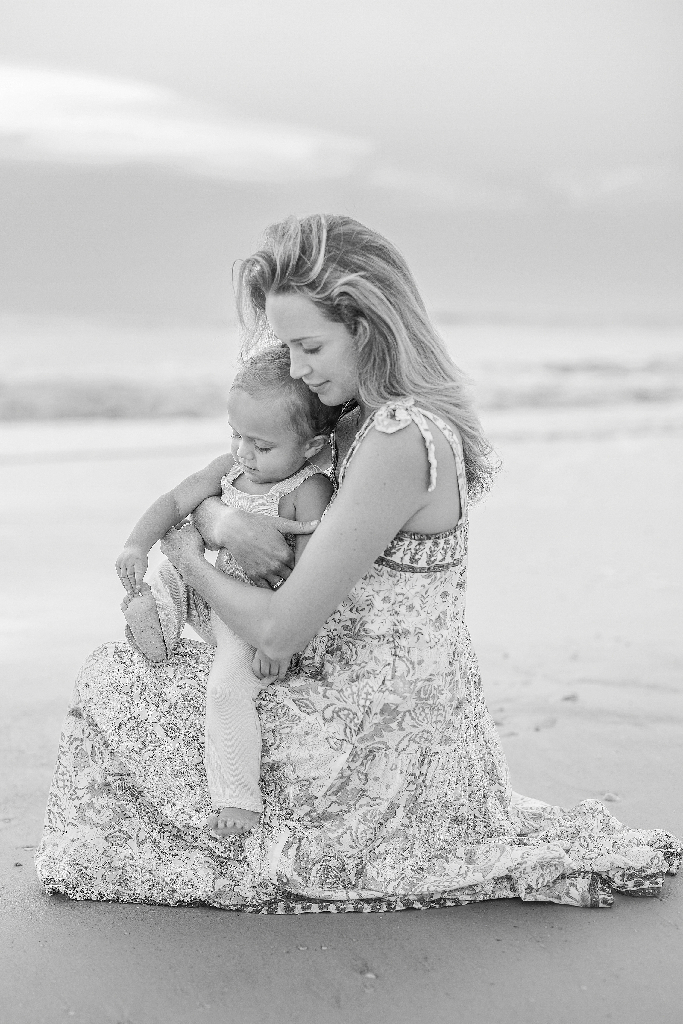 A black and white mother hood portrait on the beach at sunrise.