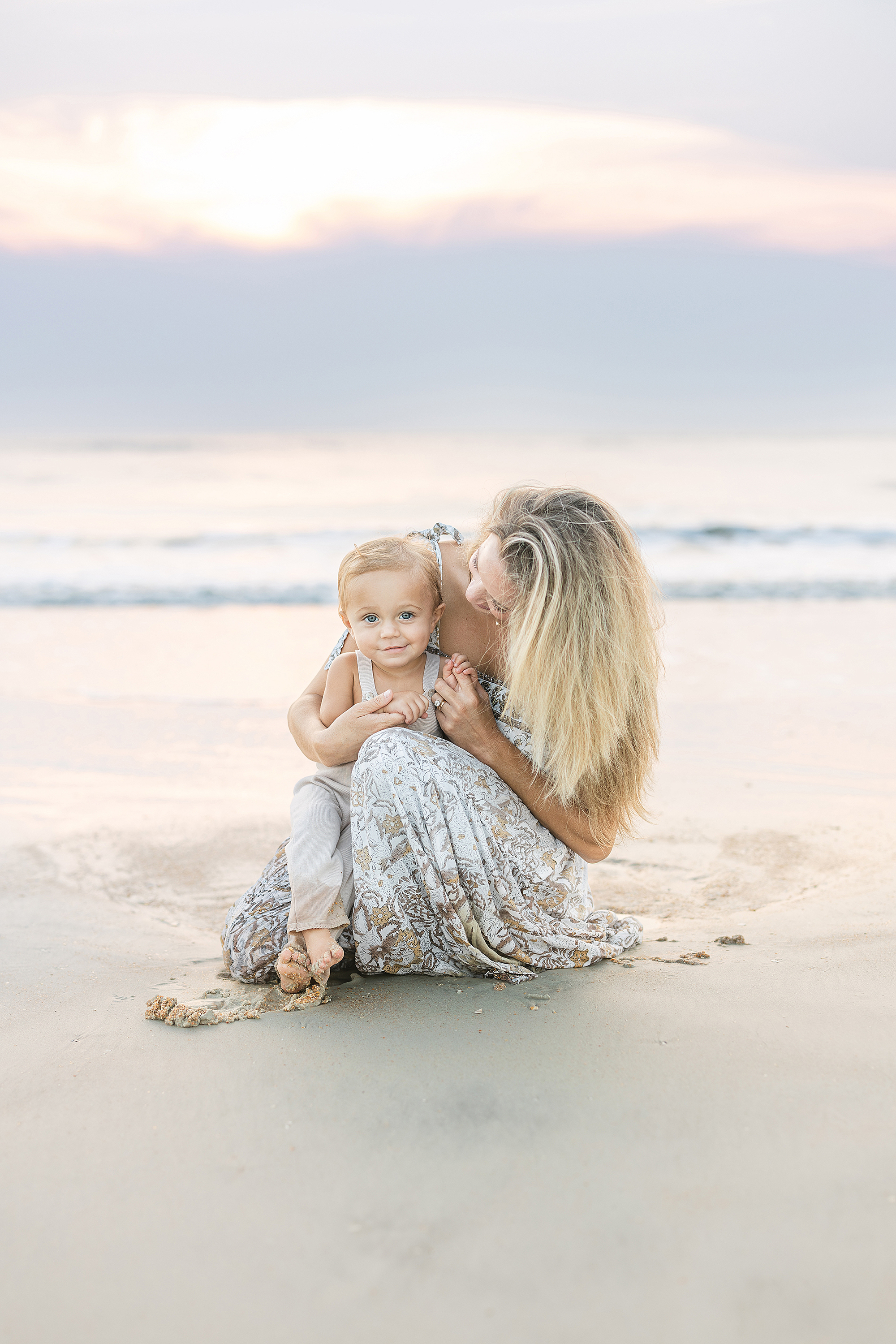 A one year old baby boy sits with his mother on the sand at St. Augustine Beach.