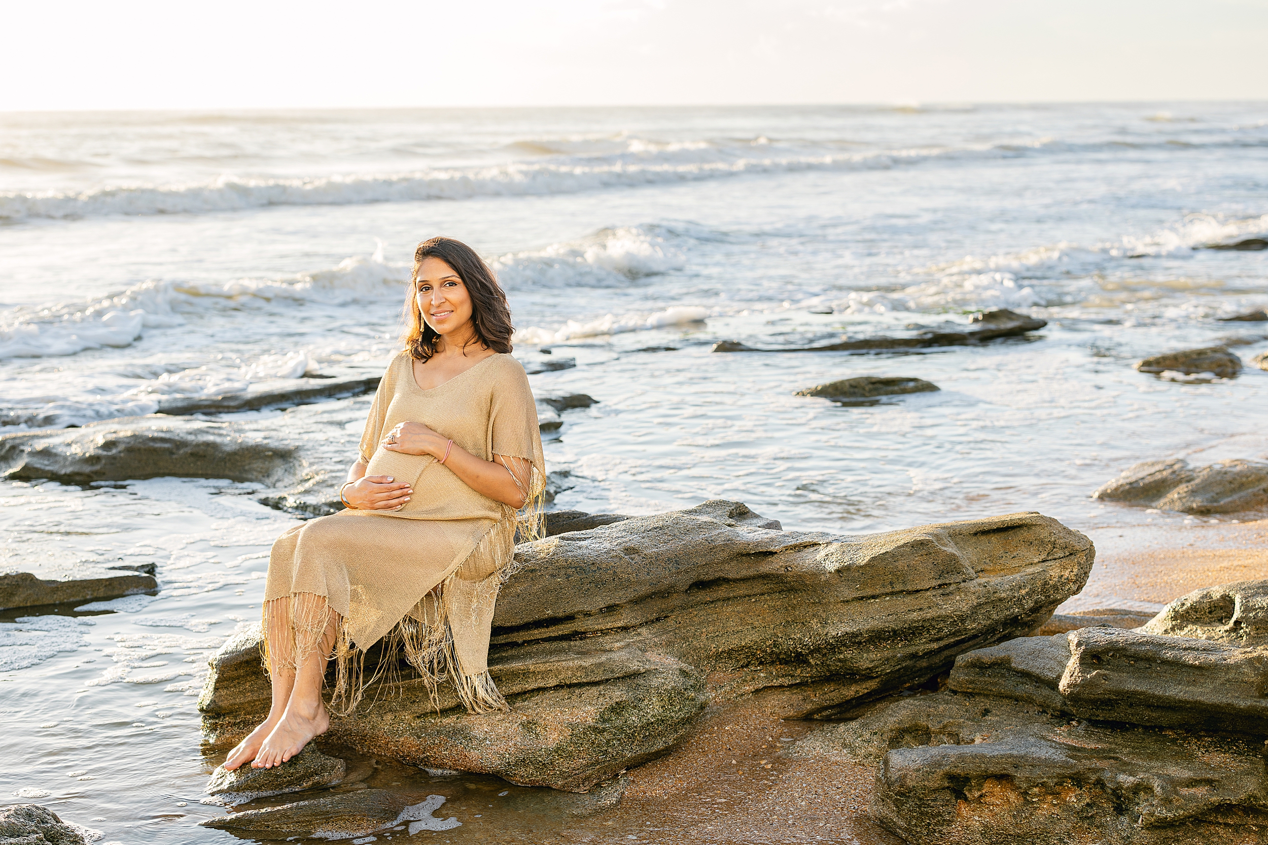 A golden-hued sunrise maternity portrait of a woman on the beach in Saint Augustine, Florida.