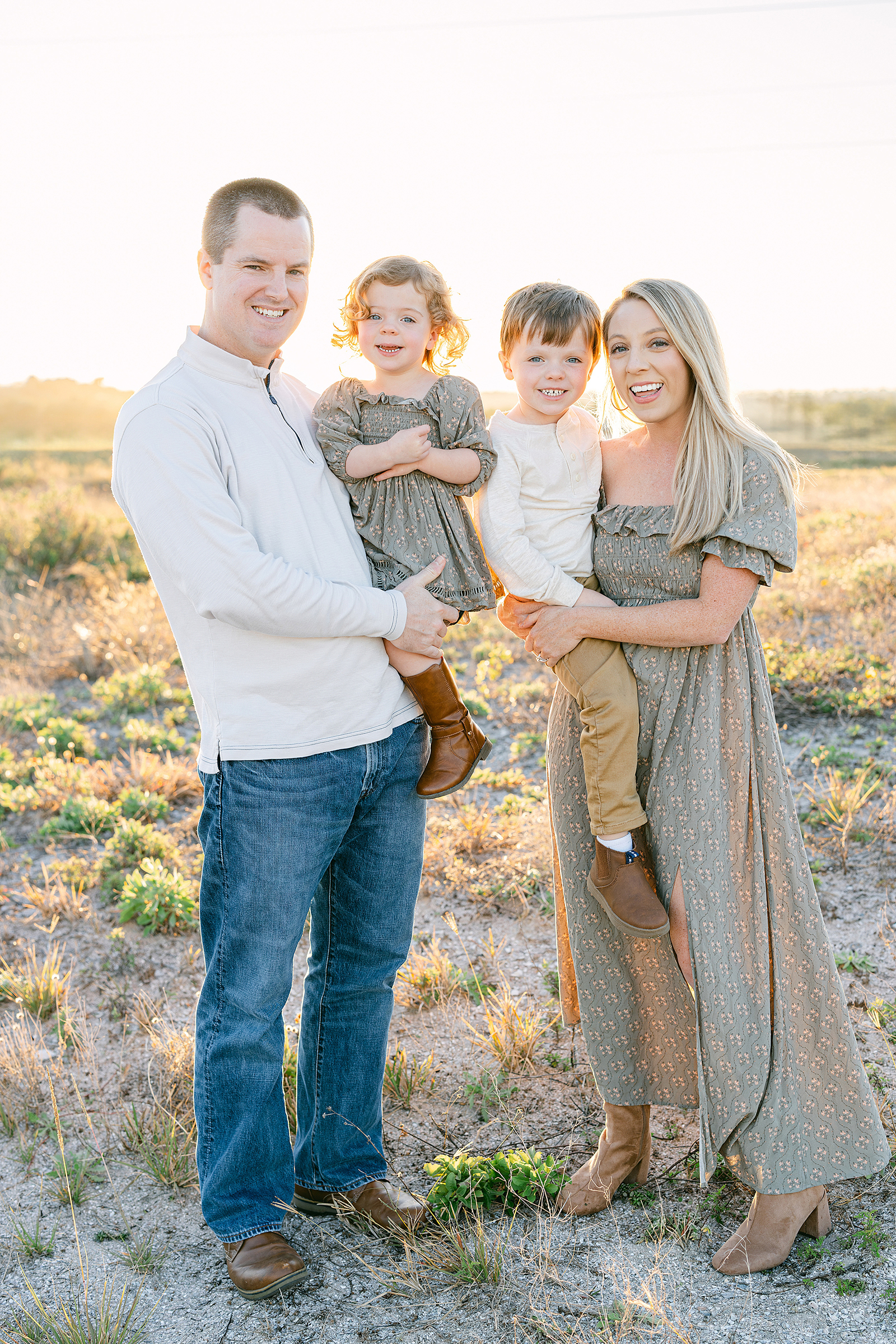 Family of four poses for a family portrait near the sand dunes in St. Augustine.