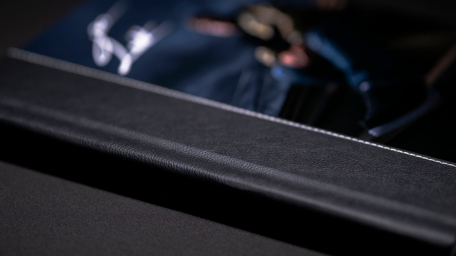 Close-up of a closed, black leather-bound book on a dark surface.