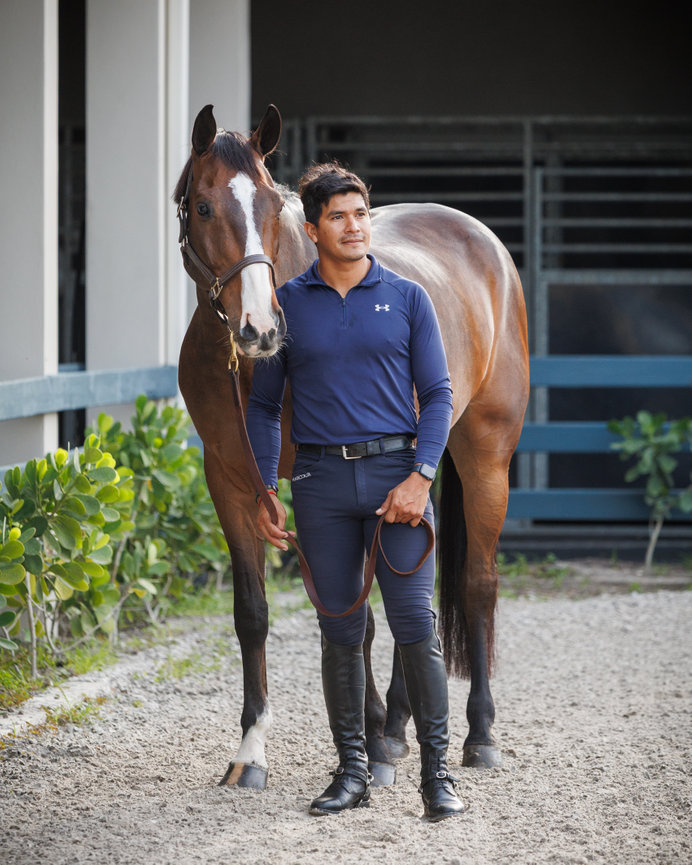Man leading a horse on a stable path outdoors