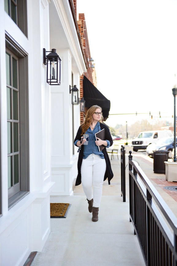 Woman walking in downtown wearing black cardigan and white pants for branding session.