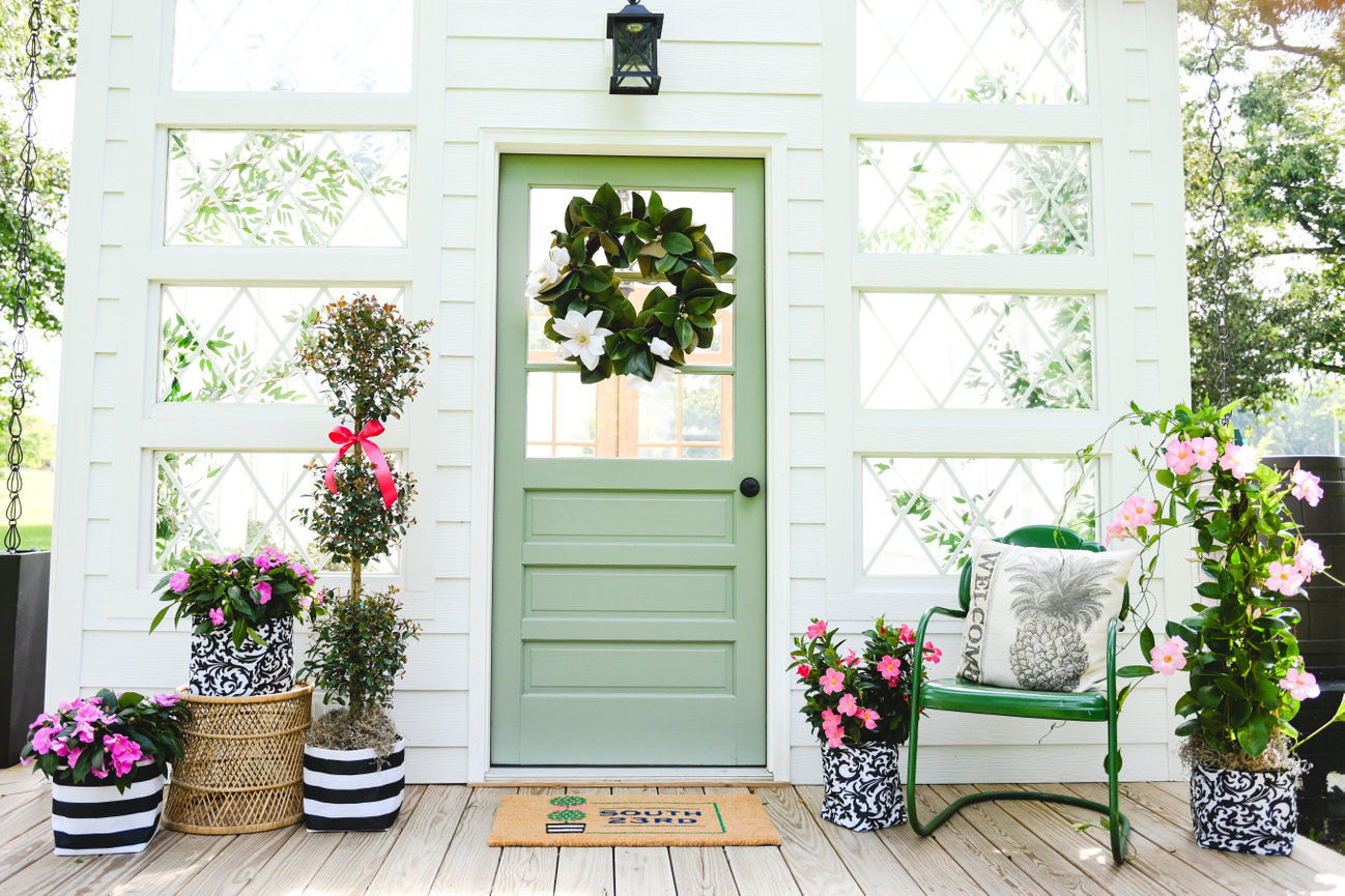 Styled porch with green door, wreath, and colorful flower planters for branding photography.