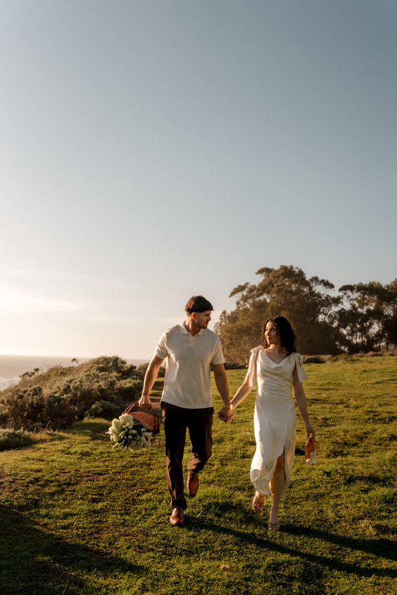 Couple holding hands walking through a field