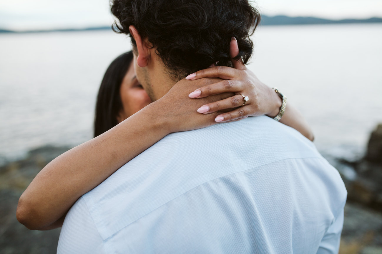 Close-up of an engagement ring as a couple embraces