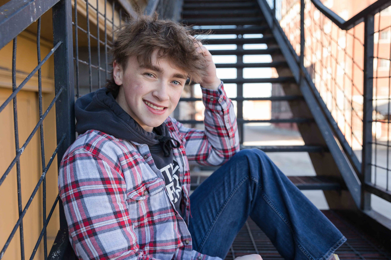 Young man sitting on stairs in a plaid shirt