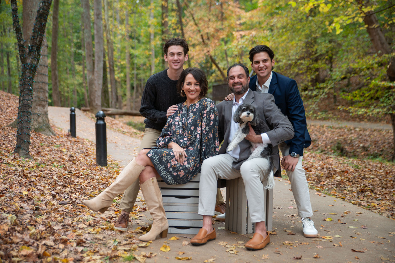 Family posing together on a forest path surrounded by trees.