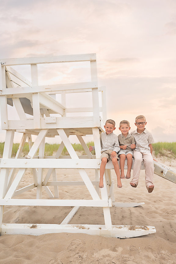 Perfectly posed all boy siblings smiling directly at camera on lifeguard stand