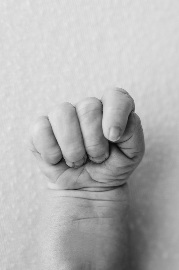 Baby’s delicate fingers in black and white, photographed in all-white Monmouth County photography space