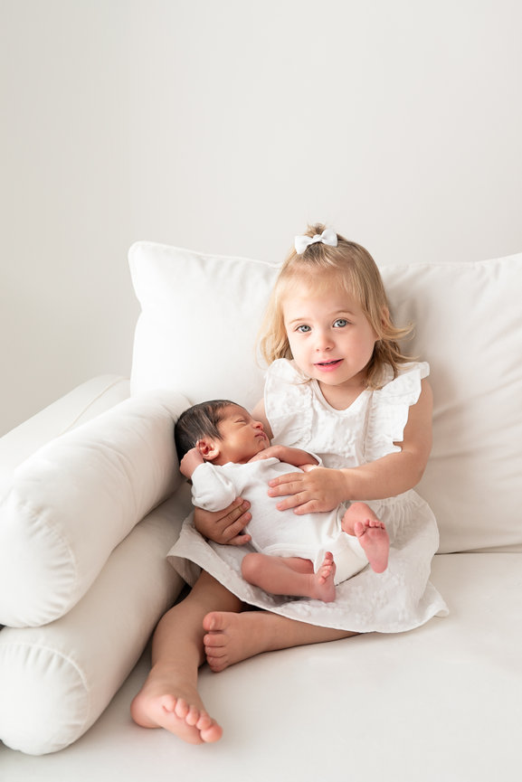 Big sister holding baby brother during lifestyle newborn session in Monmouth County