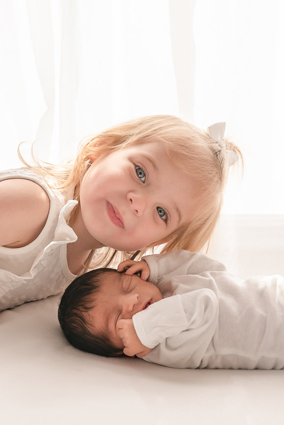 Toddler snuggled next to newborn baby during soft, organic photo session in Shrewsbury, NJ