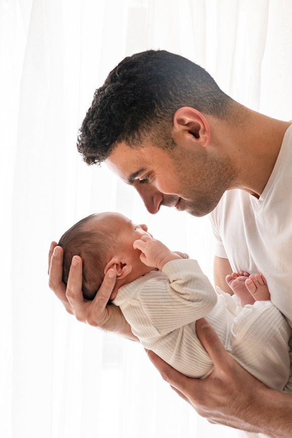 Parent cradling baby in bright, white newborn studio in Manasquan, NJ
