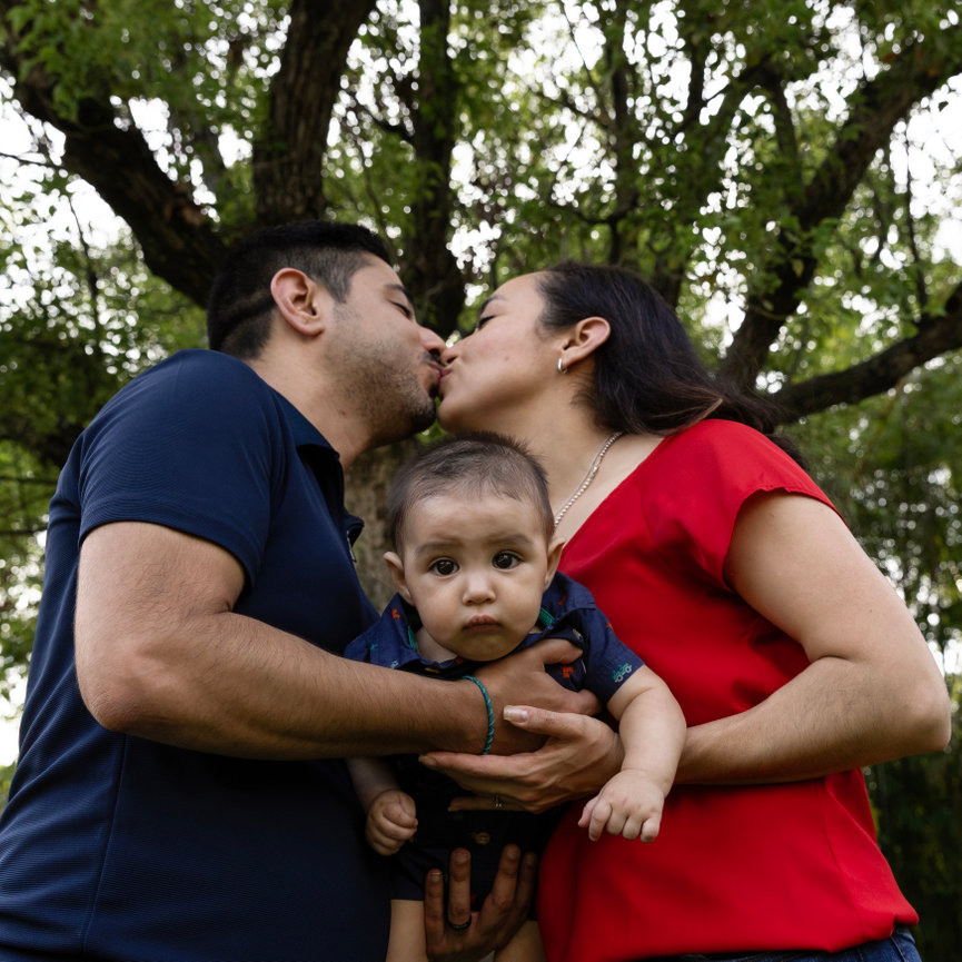 Mother and Father kissing and holding baby picture