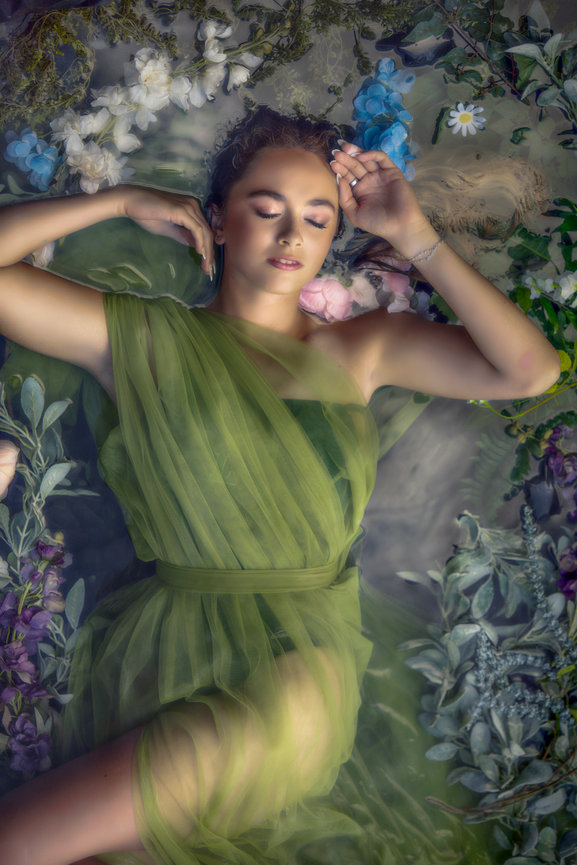 Fine art senior portrait in Colleyville with young woman in flowing green gown surrounded by flowers.
