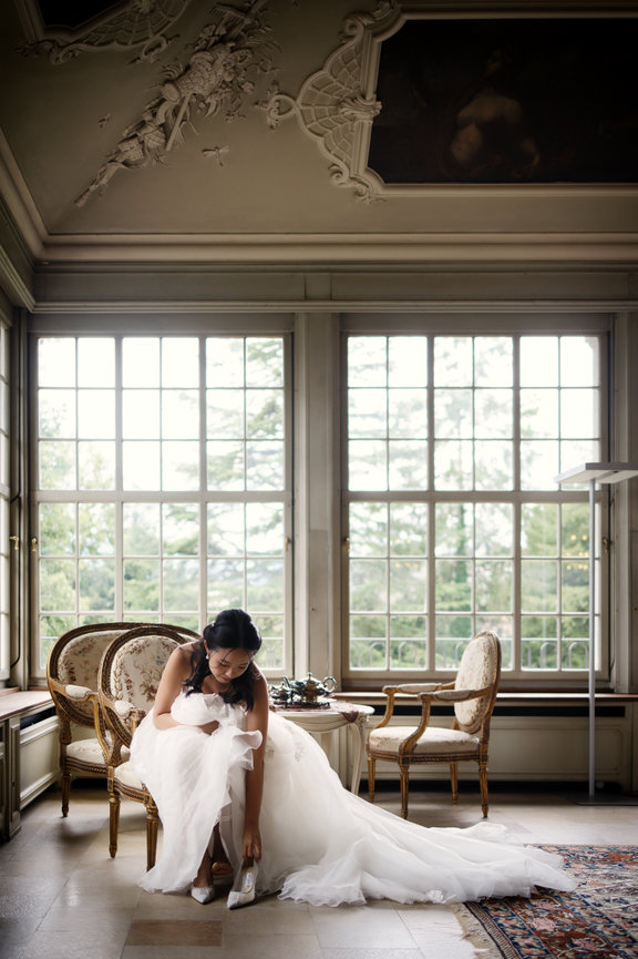 Bride in her wedding dress sitting with her dog at St. Charles Hall, Switzerland