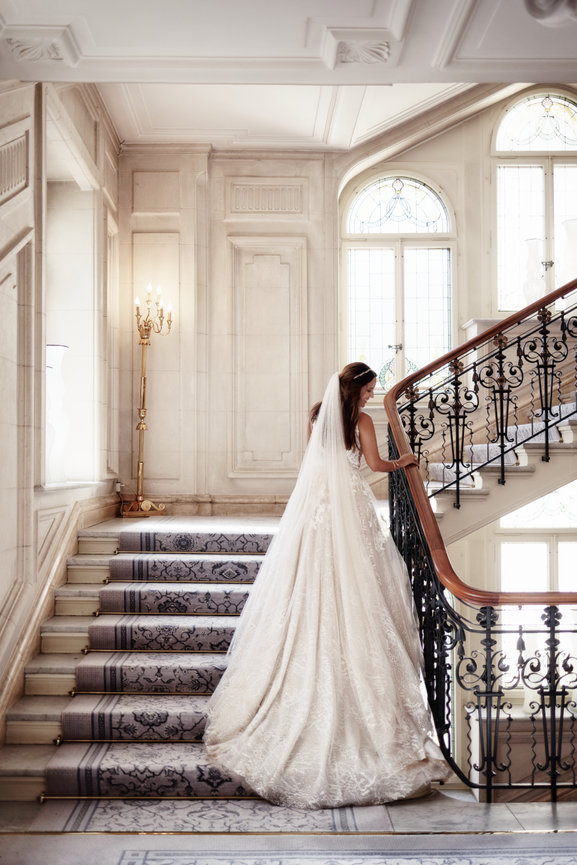 Bride in her wedding dress walking down the staircase at Beau-Rivage Palace Lausanne, Switzerland