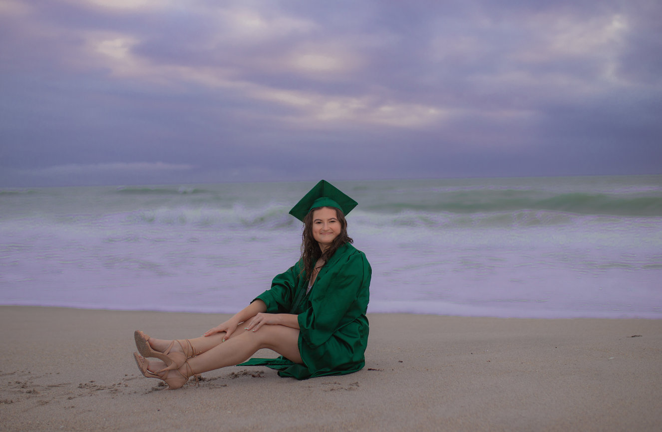 Graduate sitting on the beach with ocean view