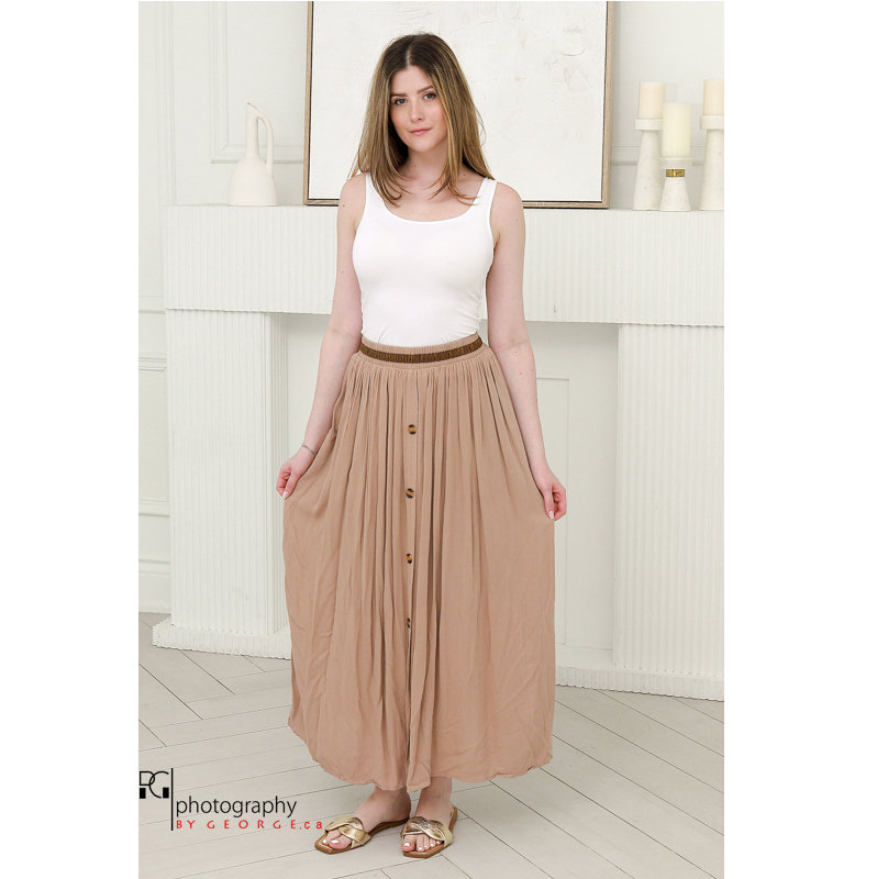Model wearing beige maxi skirt with tank top styled for spring summer fashion photoshoot in studio.