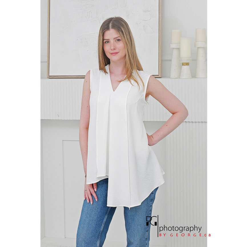 Model wearing a minimalist sleeveless cream blouse paired with denim jeans for Summer 2026 fashion.