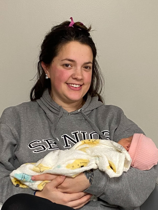 New mom sitting in salon chair holding newborn baby while getting her hair and makeup professional done for her newborn photo session with Kansas City kansas newborn photographer Dreamworks Photography 