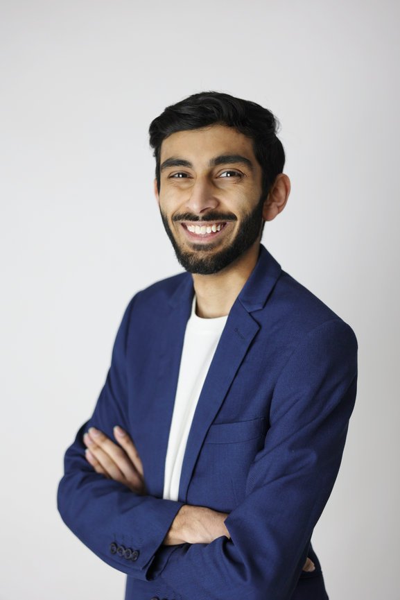Smiling man in a blue blazer with arms crossed against a plain white background. headhshot photoshoot melbourne