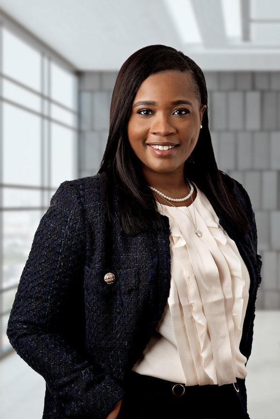 Woman smiling in an office building having her headshot taken.