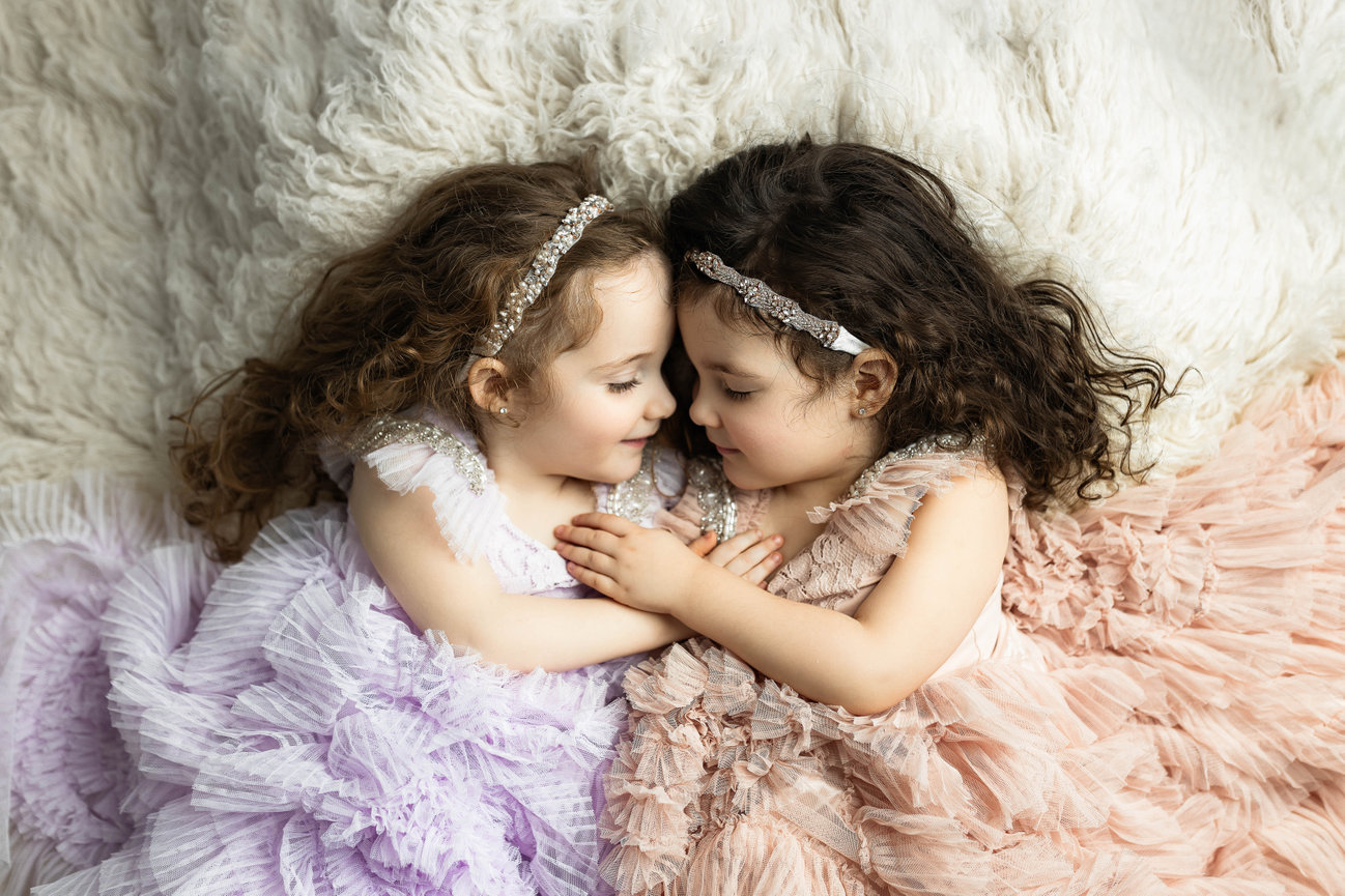 Children, sisters holding hands tulle dresses in heartfelt studio portrait